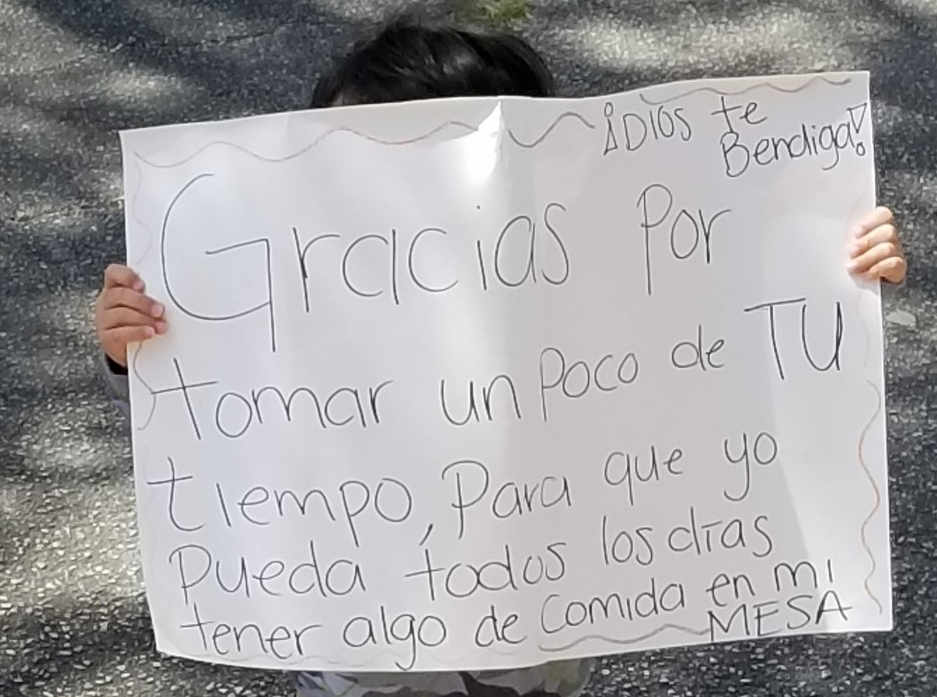 San Antonio student holds a sign thanking food workers.    